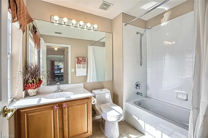 Bathroom featuring shower / tub combo, vanity, and light tile patterned flooring