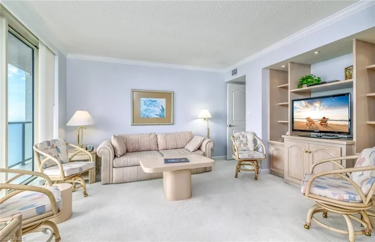 Carpeted living room with a textured ceiling and crown molding