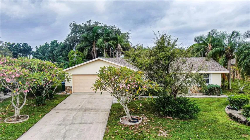View of front of house featuring driveway, a front lawn, stucco siding, and a garage
