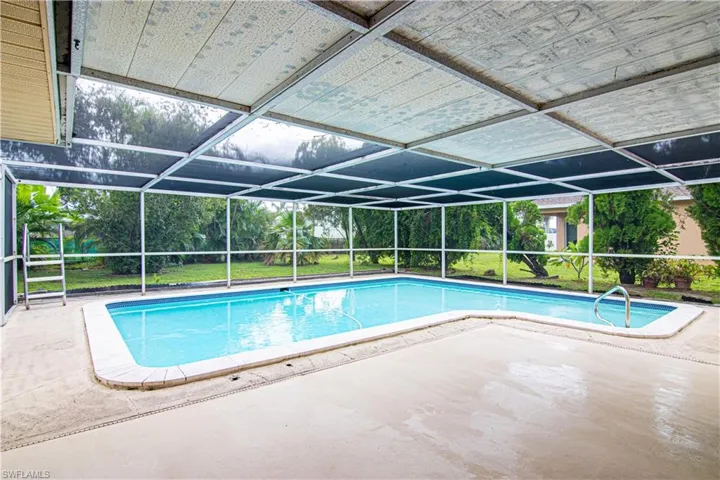 Swimming pool with glass enclosure, a patio area, and a sunroom