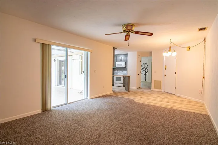 Unfurnished living room with light carpet, ceiling fan, and a chandelier
