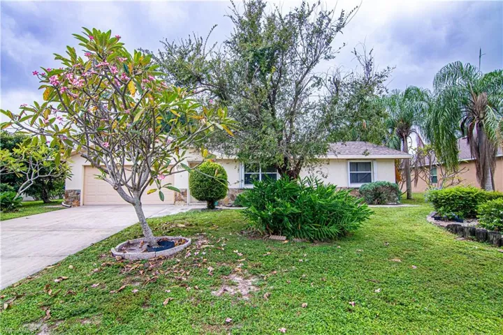 Obstructed view of property with driveway, a front yard, and stucco siding
