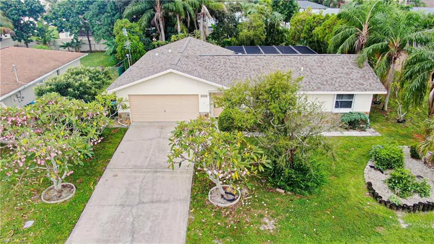 View of front of house featuring a shingled roof, stucco siding, roof mounted solar panels, a front lawn, and concrete driveway