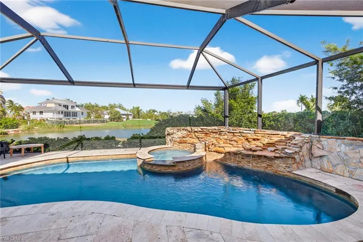 View of pool with a lanai, a sunroom, a pool with connected hot tub, and a water view