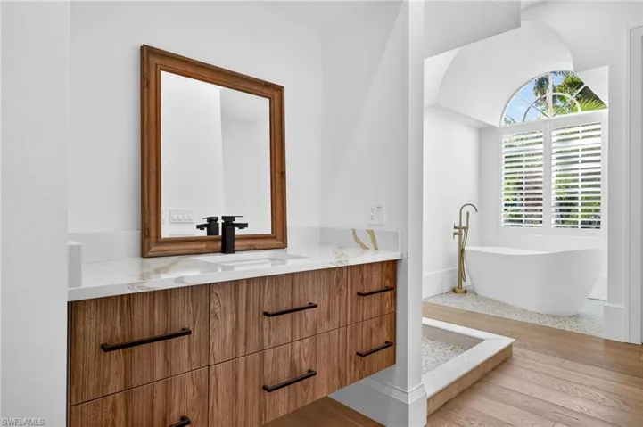 Full bathroom with vanity, a freestanding tub, and light wood-type flooring