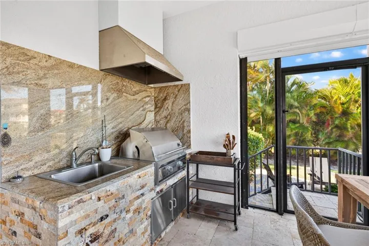 Kitchen with stone tile flooring, backsplash, wall chimney exhaust hood, and a textured wall