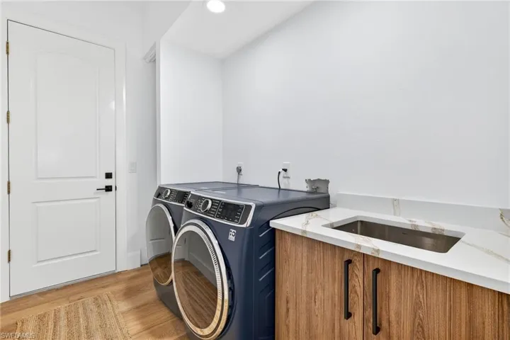 Laundry room with wood finished floors, independent washer and dryer, and recessed lighting