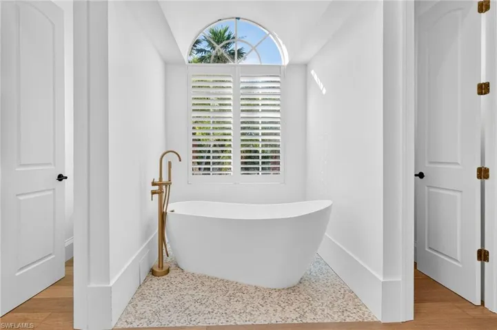 Full bathroom with a soaking tub and baseboards
