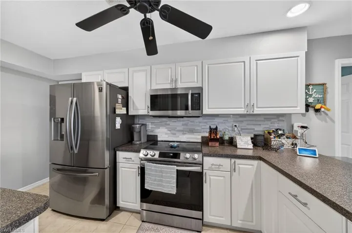 Kitchen featuring stainless steel appliances, white cabinetry, and granite-look countertops