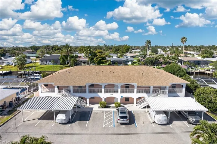 Two-story multi-unit property featuring covered parking, multiple outdoor staircases, and balconies