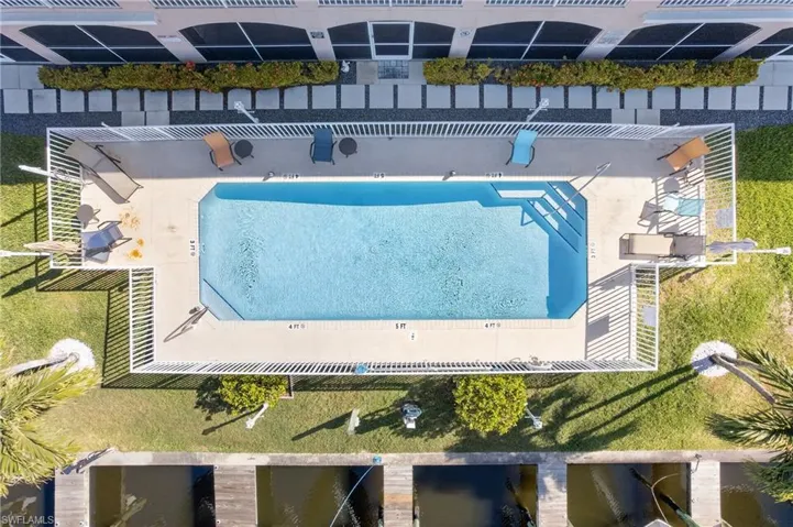 Rectangular swimming pool with integrated steps, surrounded by a white picket fence