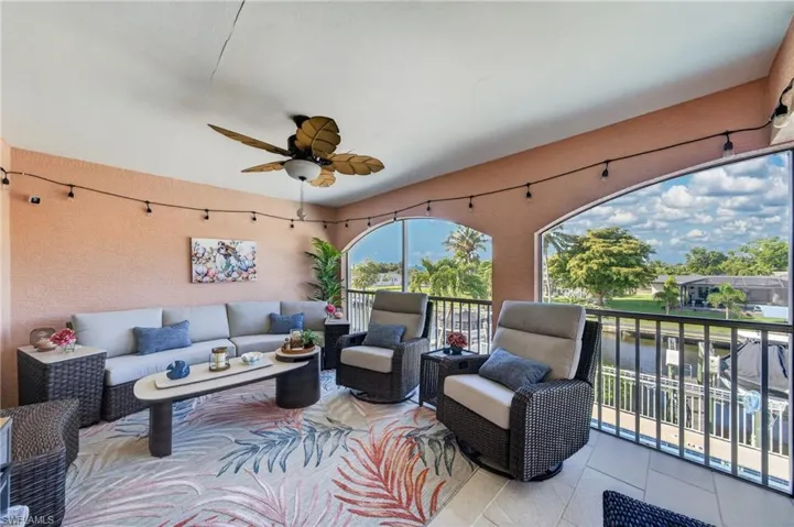 Screened lanai featuring arched openings, a ceiling fan, and string lighting