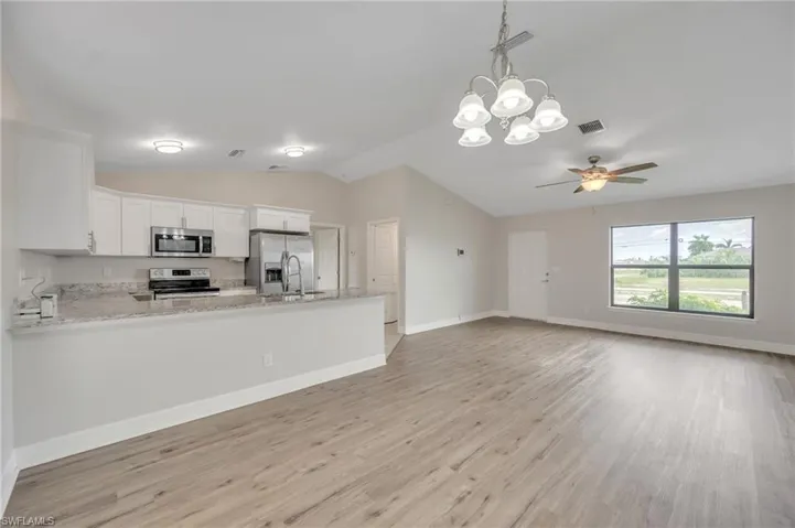 Kitchen with white cabinetry, lofted ceiling, light hardwood / wood-style floors, and appliances with stainless steel finishes