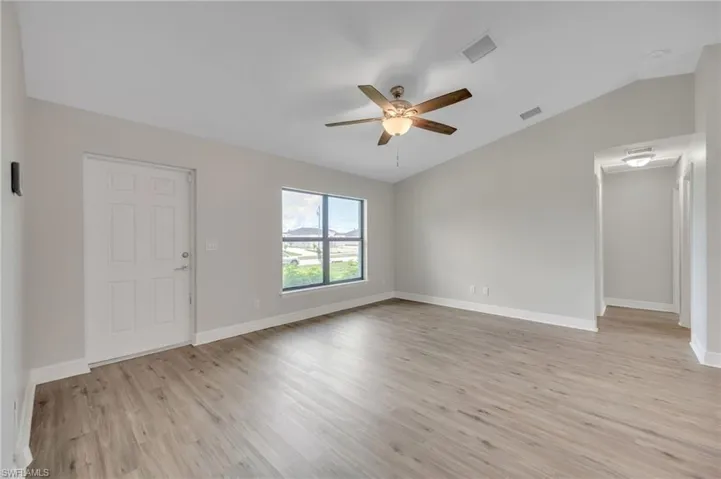Spare room with ceiling fan, lofted ceiling, and light hardwood / wood-style floors