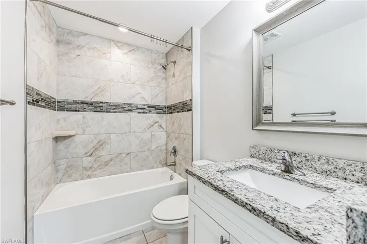 Full bathroom with vanity, toilet, tile patterned floors, and tiled shower / bath