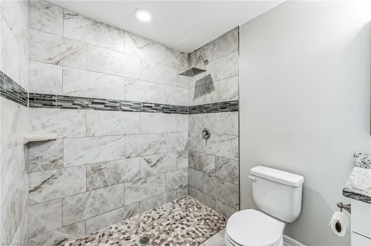 Bathroom with toilet, vanity, and a tile shower