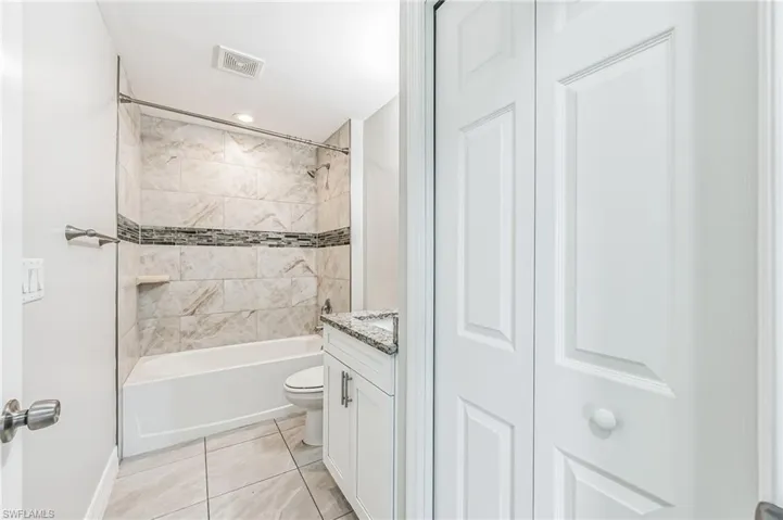 Full bathroom with vanity, toilet, tiled shower / bath, and tile patterned flooring