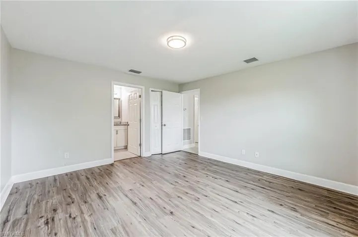 Unfurnished bedroom with wood-type flooring and connected bathroom