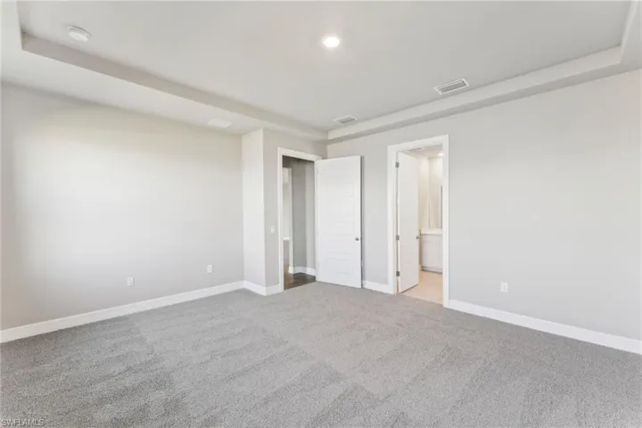 Unfurnished bedroom featuring connected bathroom and light colored carpet