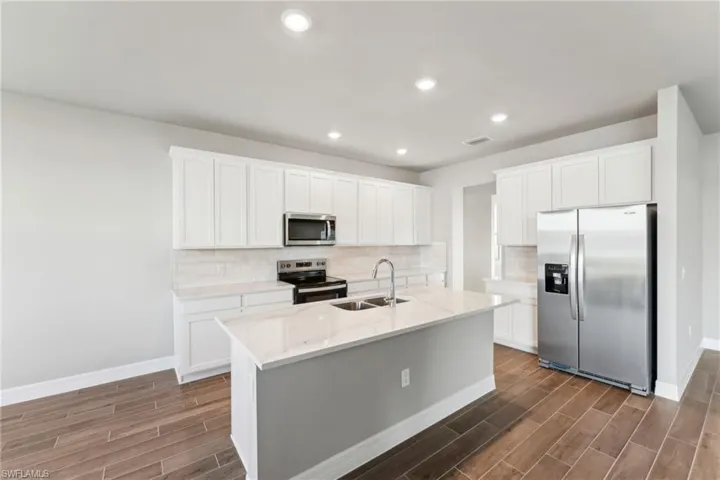 Kitchen featuring sink, decorative backsplash, white cabinets, and appliances with stainless steel finishes