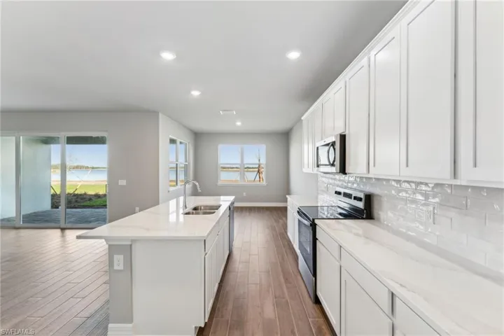 Kitchen with white cabinetry, sink, a kitchen island with sink, and appliances with stainless steel finishes