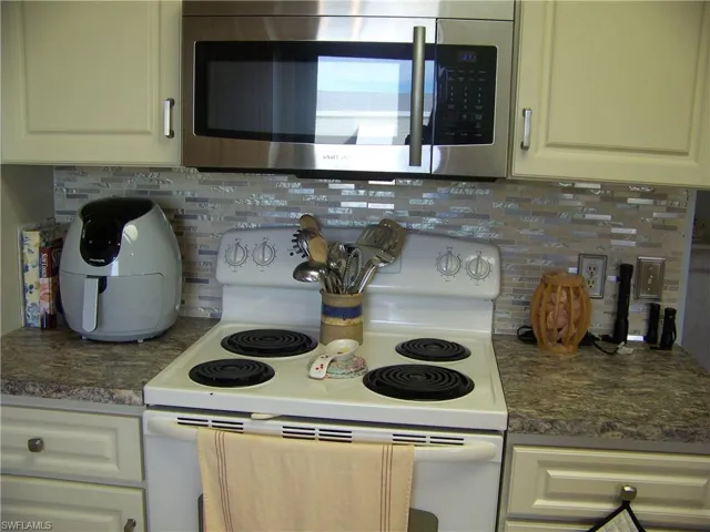 Glass backsplash, lots of raised cabinets, brushed nickel hardware.