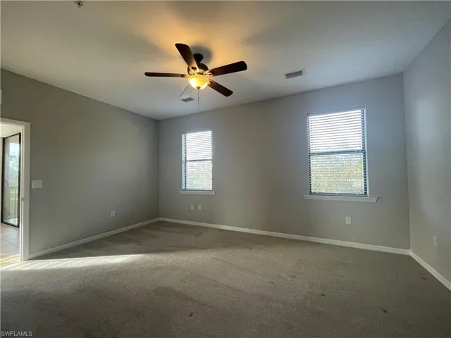 Empty room with ceiling fan and light carpet