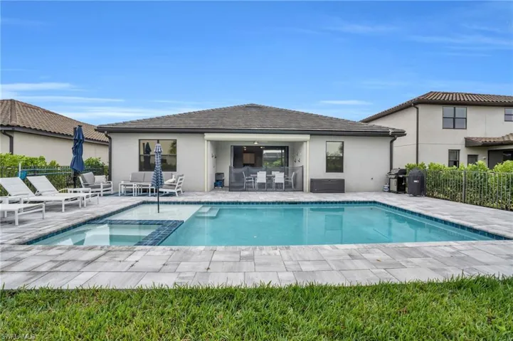 Rear view of house featuring a patio area, stucco siding, and a pool with connected hot tub