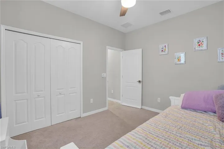 Bedroom featuring light carpet, a ceiling fan, and a closet