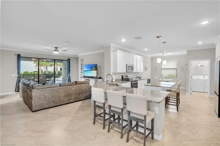 Kitchen with a peninsula, a kitchen bar, a center island, pendant lighting, and crown molding