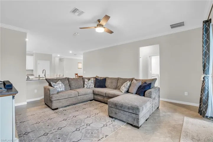 Tiled living area with ornamental molding and a ceiling fan