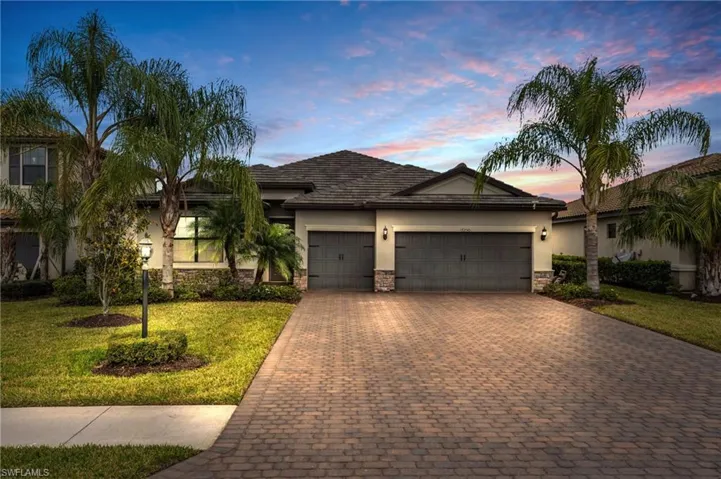 Ranch-style house featuring stone siding, stucco siding, a front lawn, decorative driveway, and an attached garage