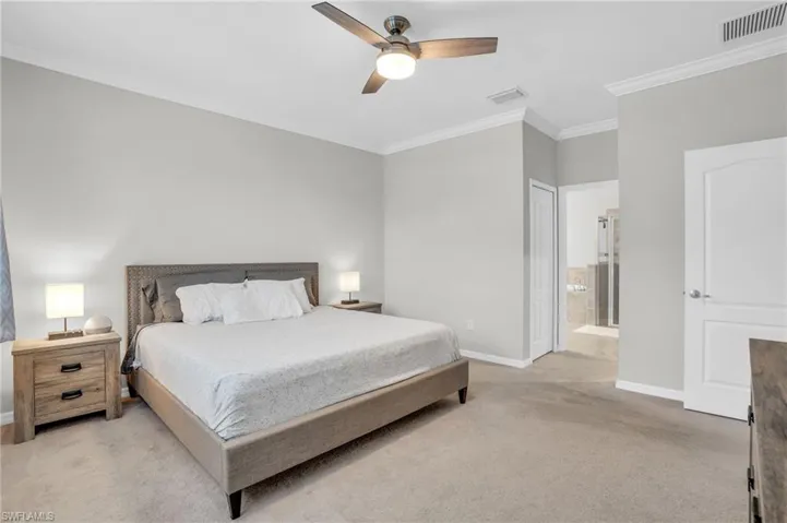 Bedroom featuring crown molding, light carpet, ensuite bathroom, and ceiling fan
