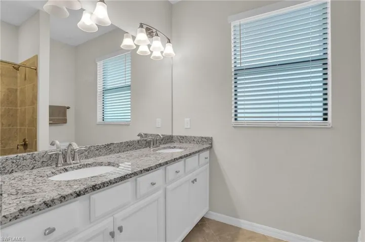 Full bath featuring double vanity and light tile patterned flooring