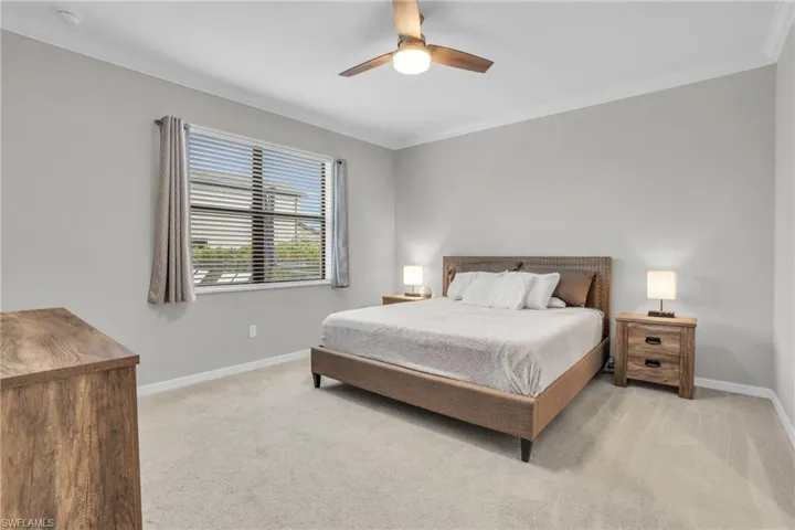 Bedroom featuring crown molding, light carpet, and a ceiling fan