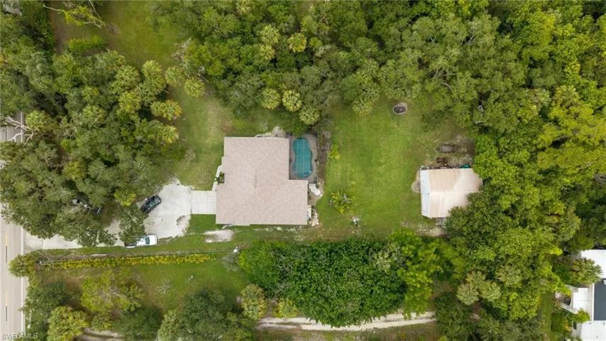 Aerial perspective of a property with a main residence, an in-ground swimming pool, and an auxiliary structure