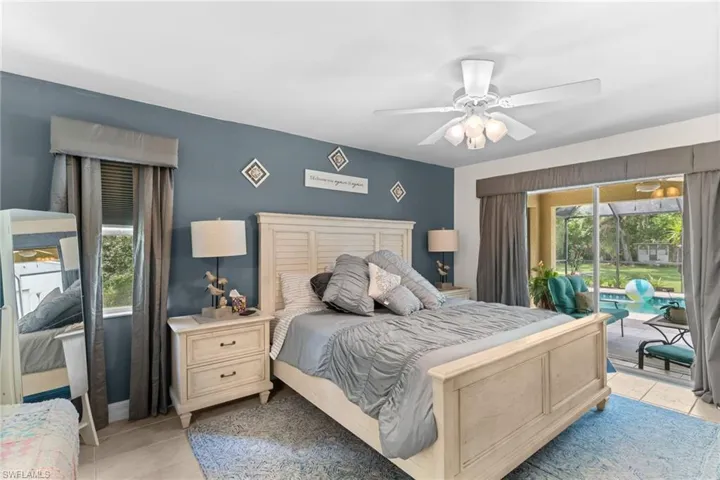 Bedroom featuring neutral tile flooring, a ceiling fan with integrated lighting, and direct access to an outdoor area through glass sliding doors