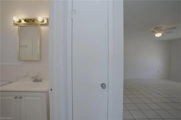 The property features a bathroom with a vanity, mirror, and overhead lighting fixture, and a separate room with tiled flooring and a ceiling fan
