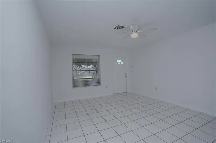 This bright room features tiled flooring, white walls, and a ceiling fan with integrated lighting