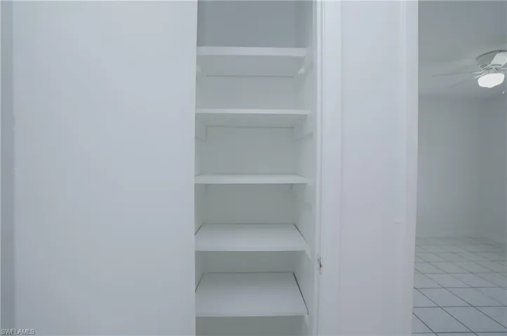 Built-in shelving unit providing storage space, with tile flooring and a ceiling fan visible in the background