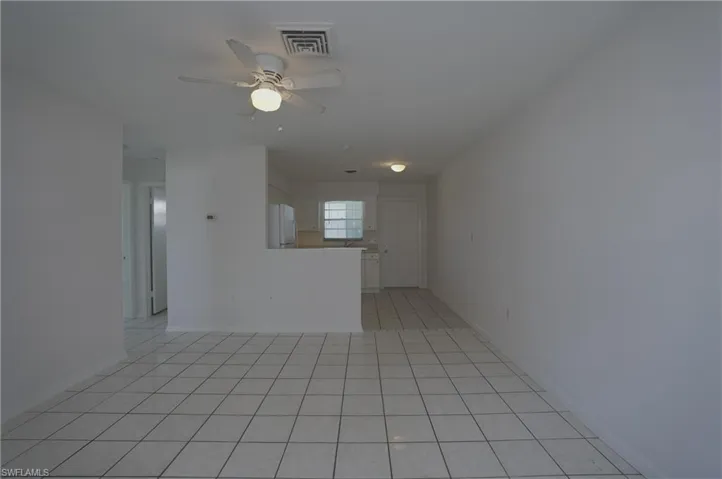 The living area features white tile flooring, a ceiling fan with integrated lighting, and white painted walls