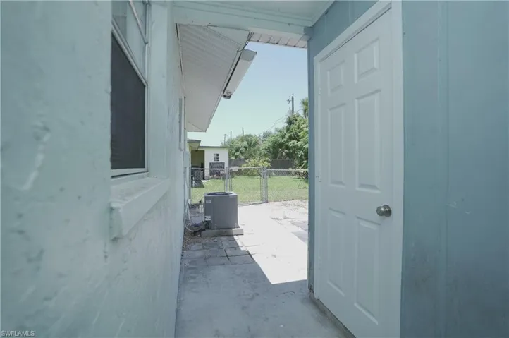 The property features an exterior with light-colored siding, a window with blinds, and a white door