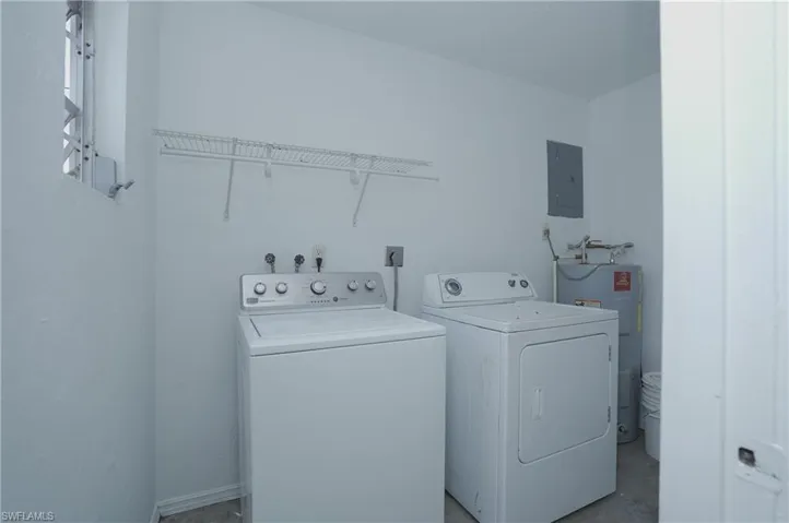 Dedicated laundry area featuring a washer, dryer, and an overhead wire shelf for storage