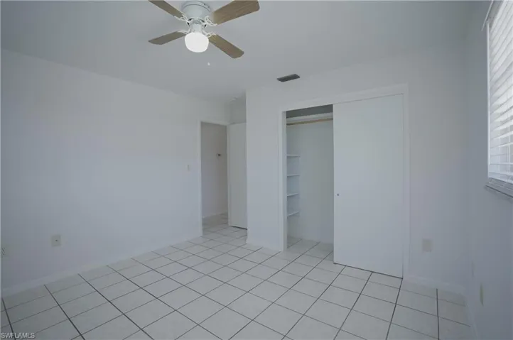 Room with white walls, tiled flooring, and a ceiling fan