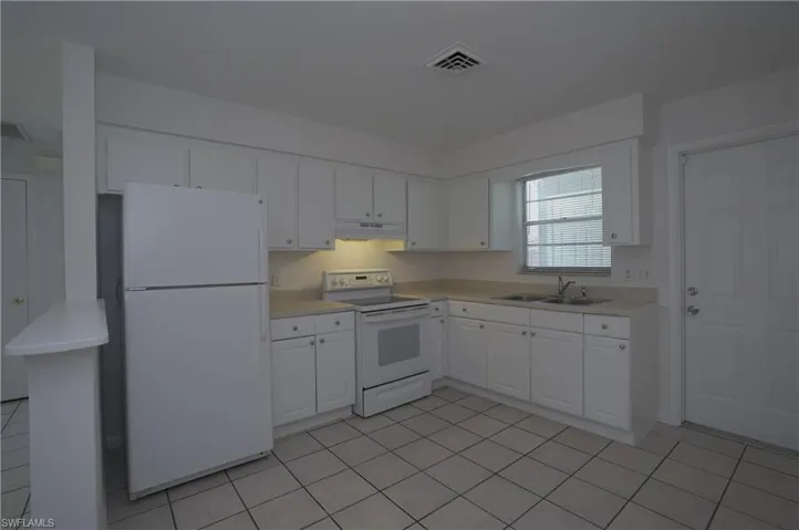 Kitchen featuring white cabinetry, a refrigerator, an oven, and a double basin sink