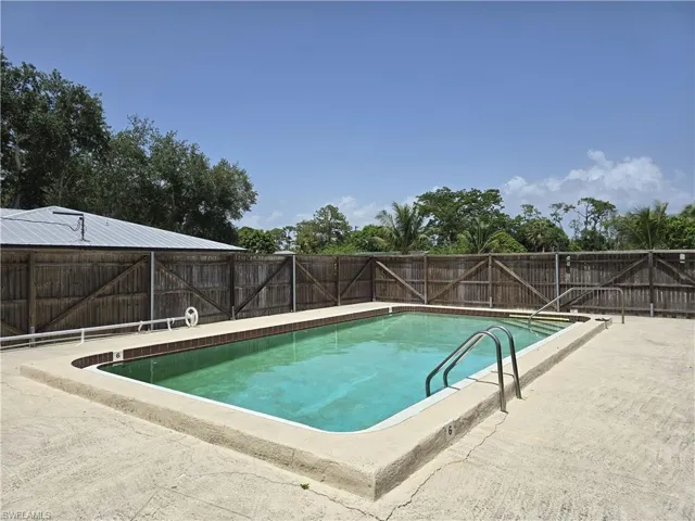 Community pool with a fenced backyard and a patio area