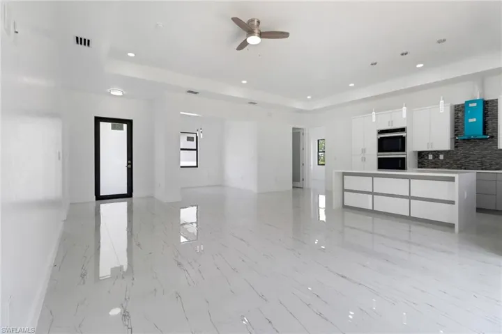 Kitchen with modern cabinets, extractor fan, a ceiling fan, a raised ceiling, and recessed lighting