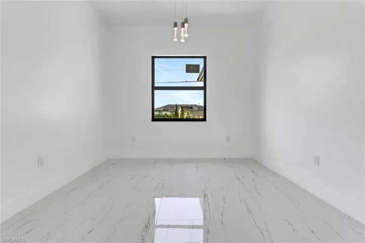 Empty room featuring marble look tiles and a chandelier