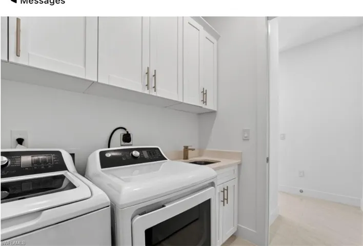 Dedicated laundry space featuring white shaker cabinetry with brushed brass hardware, a light-toned countertop, and a utility sink with a brass faucet
