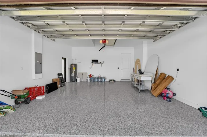 Spacious garage featuring a speckled epoxy floor, white painted walls, and a water heater